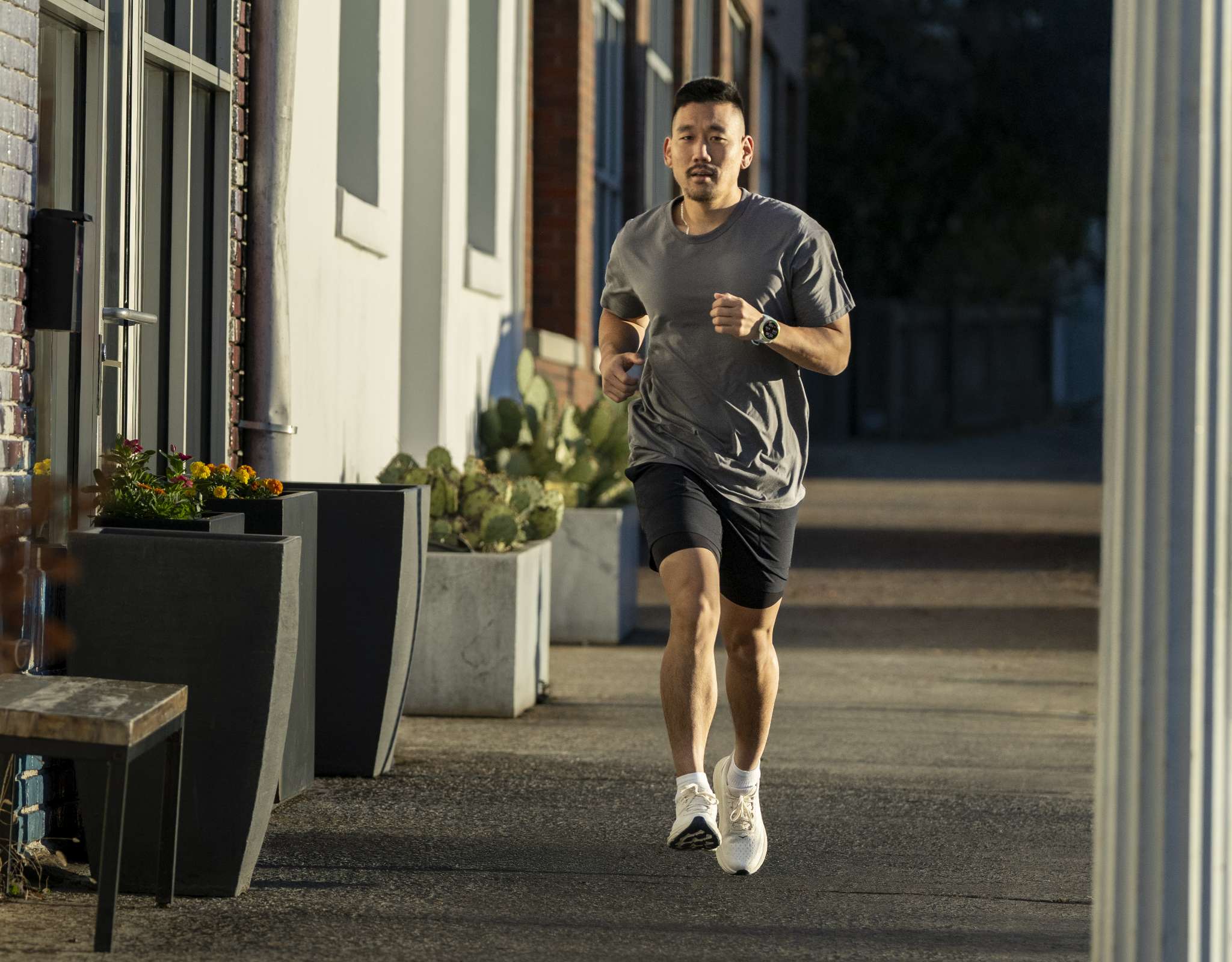 Man rent op stoep in stedelijke omgeving met sporthorloge en sportkleding.